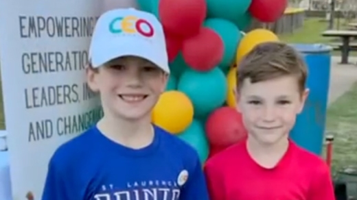 Two young boys smiling in front of a balloon arch